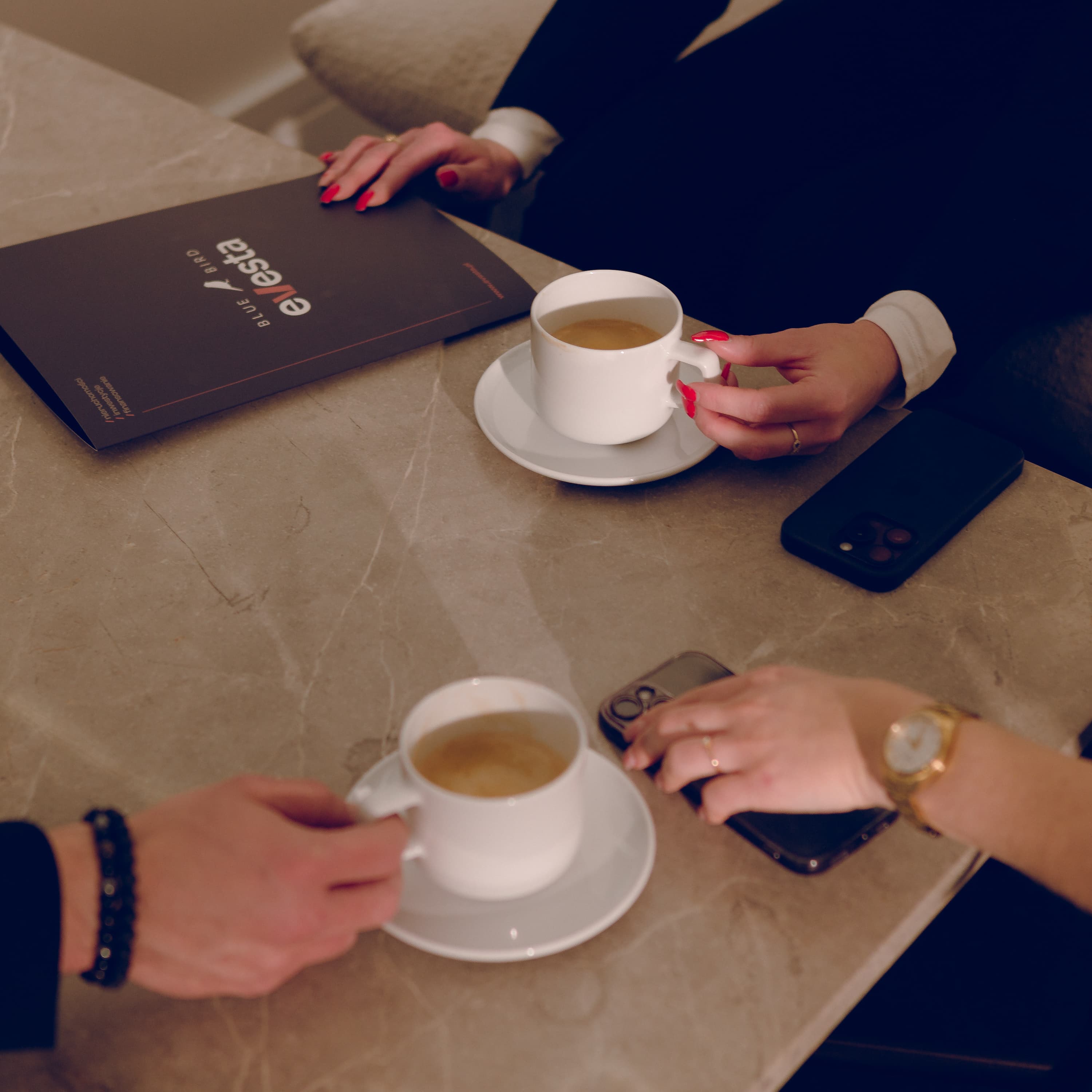 The photo shows 3 pairs of hands on a conference table.